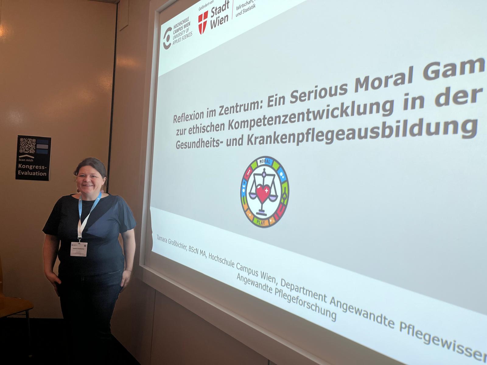 Eine Referentin steht neben einer Präsentationsfolie mit dem Titel des Vortrags „Reflexion im Zentrum“