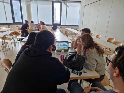 Studierende arbeiten in einem Seminarraum gemeinsam an einem Laptop
